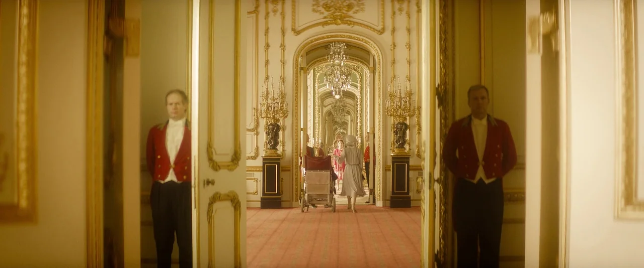 The Theory of Everything (2014) movie still: wide — An opulent palace corridor with long rows of arches and ornate golden wall fixtures. A woman in…