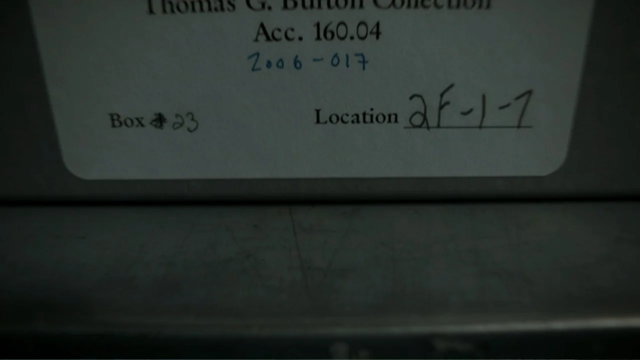 Alabama Snake (2020) movie still: closeup — A grey storage container with an attached white paper label. Hand-written and typed text details…