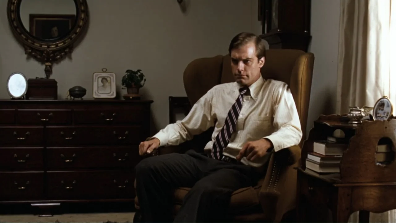 All the President's Men (1976) movie still: medium — A traditional living room features wooden furniture, a framed portrait, and a houseplant. A man…