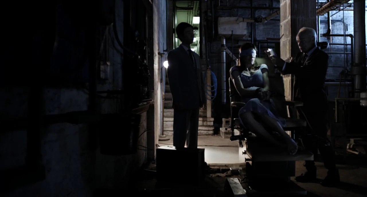 Brawl in Cell Block 99 (2017) movie still: wide — A dark, unfinished basement with exposed brick walls and various pipes along the ceiling. A man in…