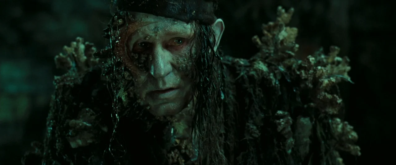 Pirates of the Caribbean: Dead Man’s Chest movie still: closeup — A dark, shadowy environment filled with damp textures and organic marine debris. A…