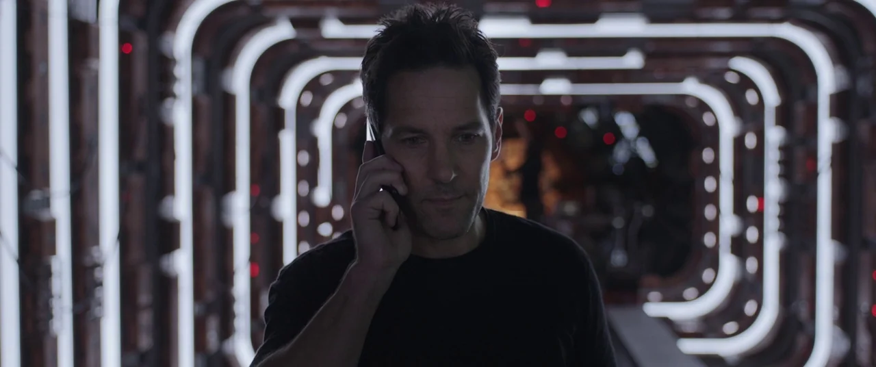 Ant-Man and the Wasp (2018) movie still: medium — A narrow tech-filled tunnel contains rows of glowing white rectangular light fixtures. A man in a…