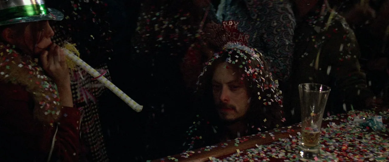 Forrest Gump (1994) movie still: medium — A dimly lit bar surface is covered in multi-colored paper confetti during a celebration. A man sits…