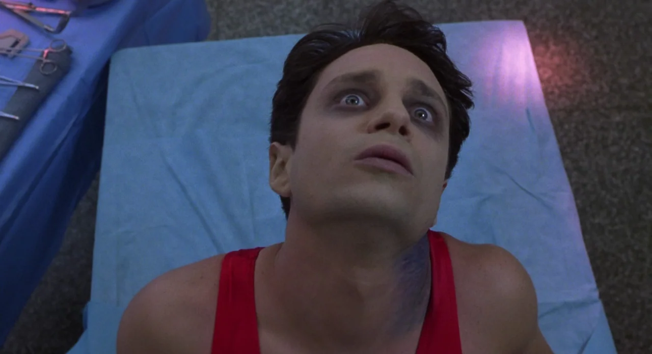 Monkeybone (2001) movie still: closeup — A medical examination room features a sterile blue sheet and stainless steel instruments. A young man lies…