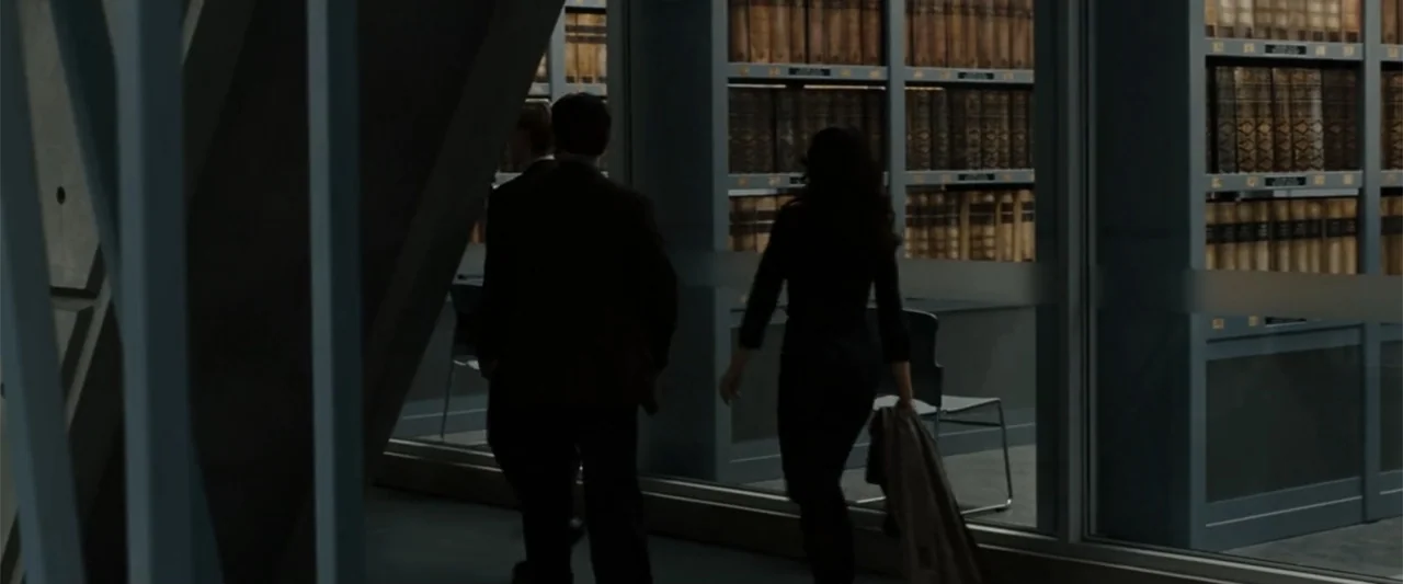 Angels & Demons (2009) movie still: medium — An interior space features glass-enclosed walls lined with numerous shelves of thick, bound volumes.…