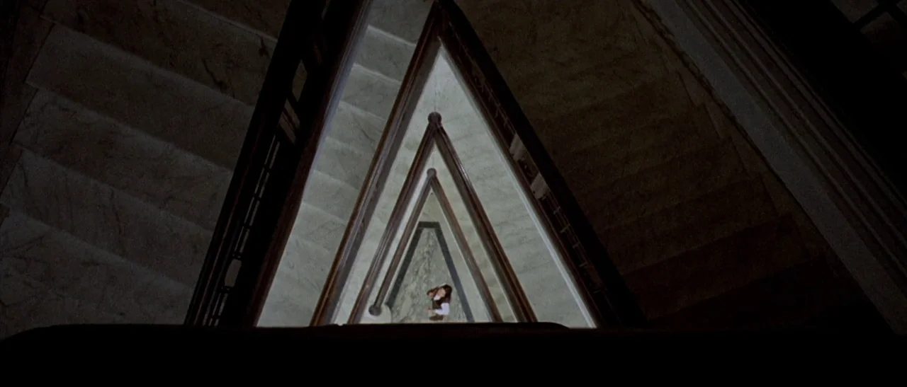 The Bird With The Crystal Plumage (1970) movie still: wide — A top-down view shows the triangular opening of a marble staircase with wooden…