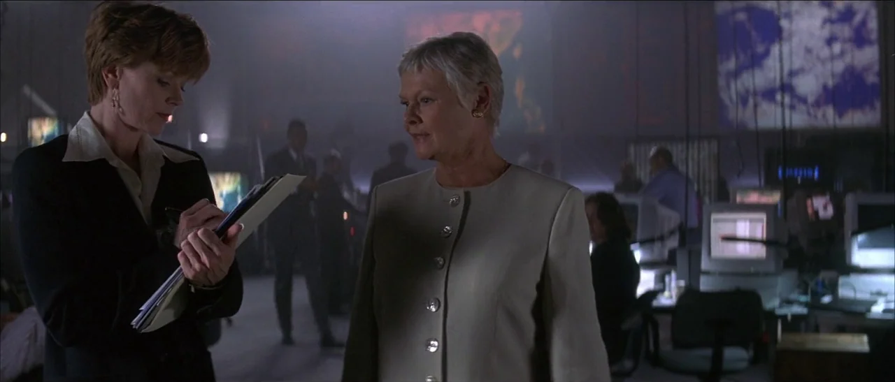 Tomorrow Never Dies (1997) movie still: medium — A dimly lit command center features multiple large monitors and computer workstations in darkness.…