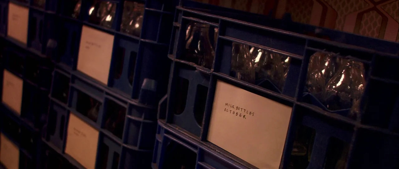 Bunny and the Bull (2009) movie still: medium — Rows of blue plastic crates are stacked in a dimly lit, organized storage space. Each crate holds…
