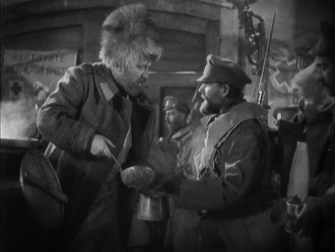 The Last Command (1928) movie still: medium — A crowded communal space where men in military uniforms gather around a cooking station. One man holds…