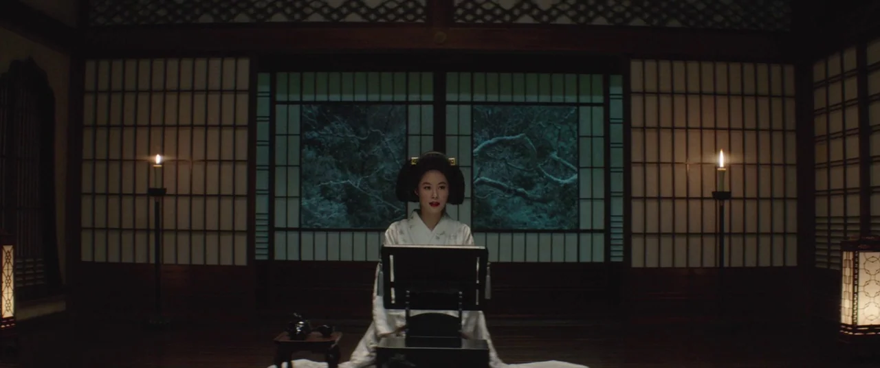 The Handmaiden (2016) movie still: medium — A traditional room features sliding paper doors revealing dark foliage through a central window. A woman…