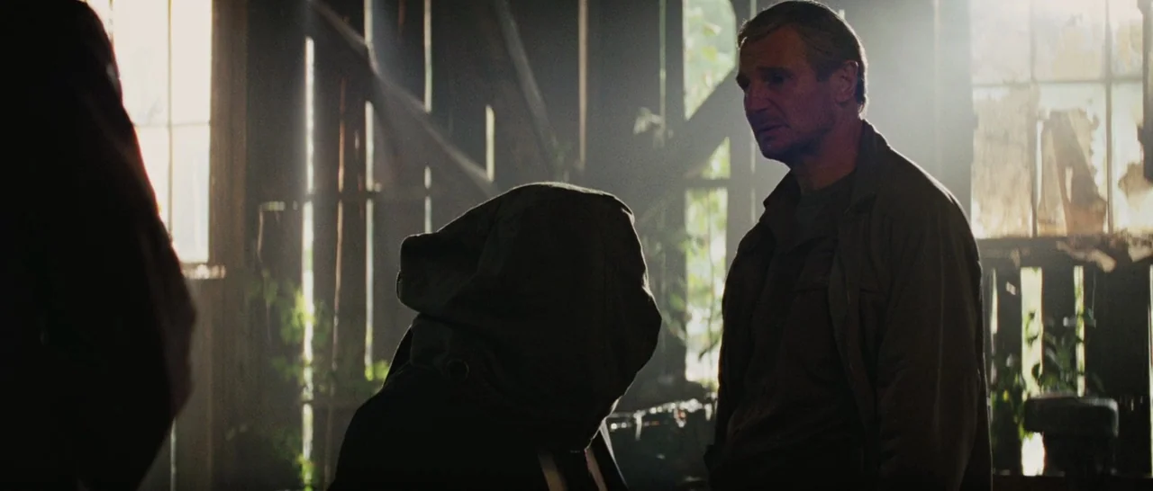 The A-Team (2010) movie still: medium — A dark wooden shed with narrow slats of sunlight cutting through dusty interior space. An older man stands…