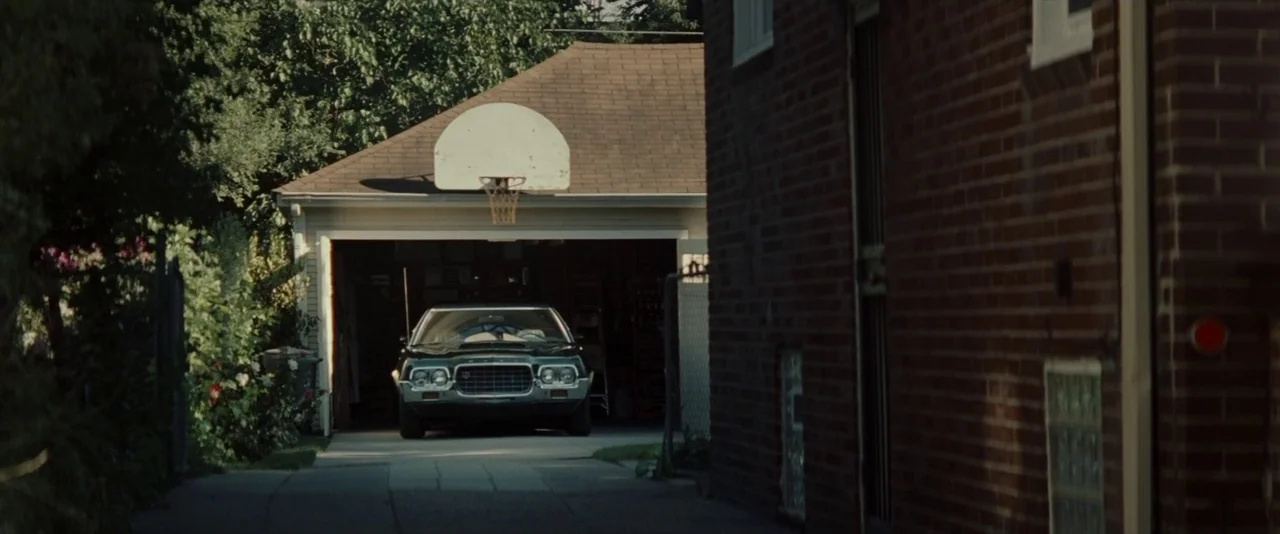 Gran Torino (2008) movie still: wide — A narrow residential alleyway sits between a brick building and a detached residential garage. A vintage…