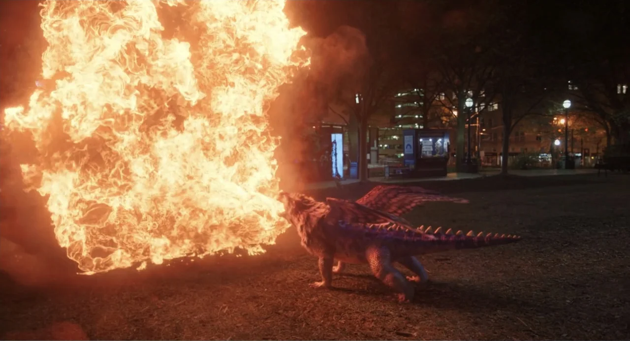 Harold and the Purple Crayon (2024) movie still: wide — A nighttime park setting features a grassy area illuminated by an intense fire blast. A…