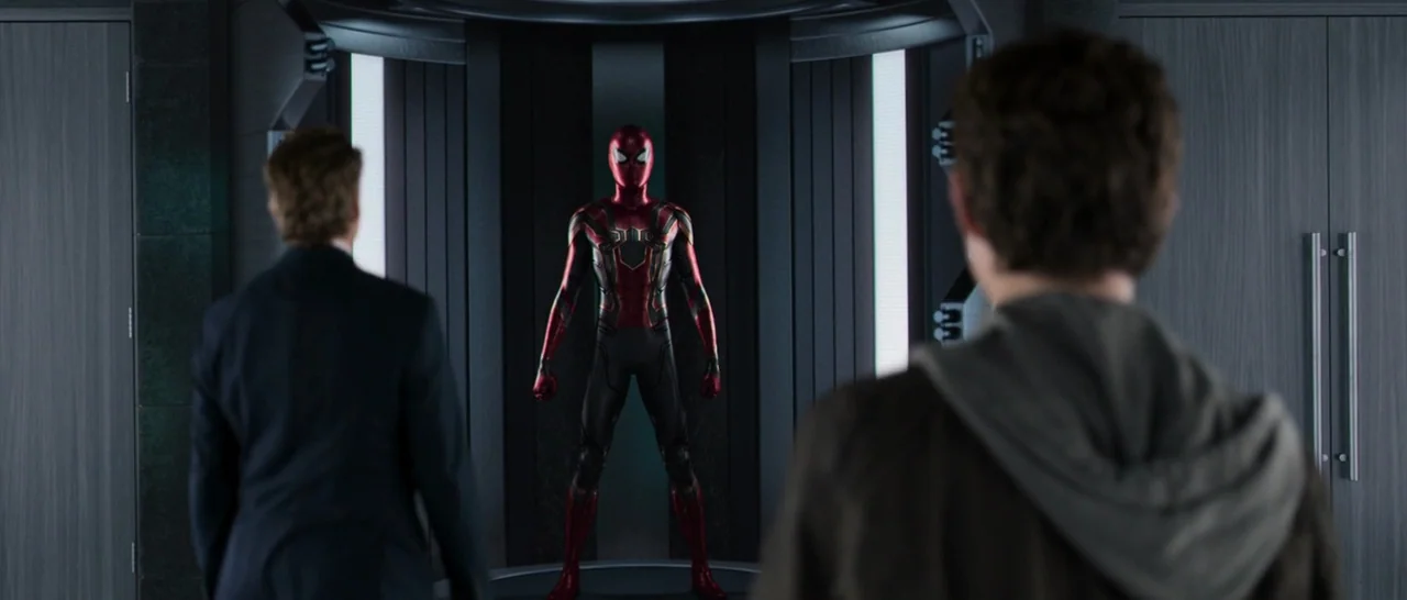 Spider Man: Homecoming (2017) movie still: medium — A high-tech metallic chamber features a centralized display unit holding an armored red suit.…