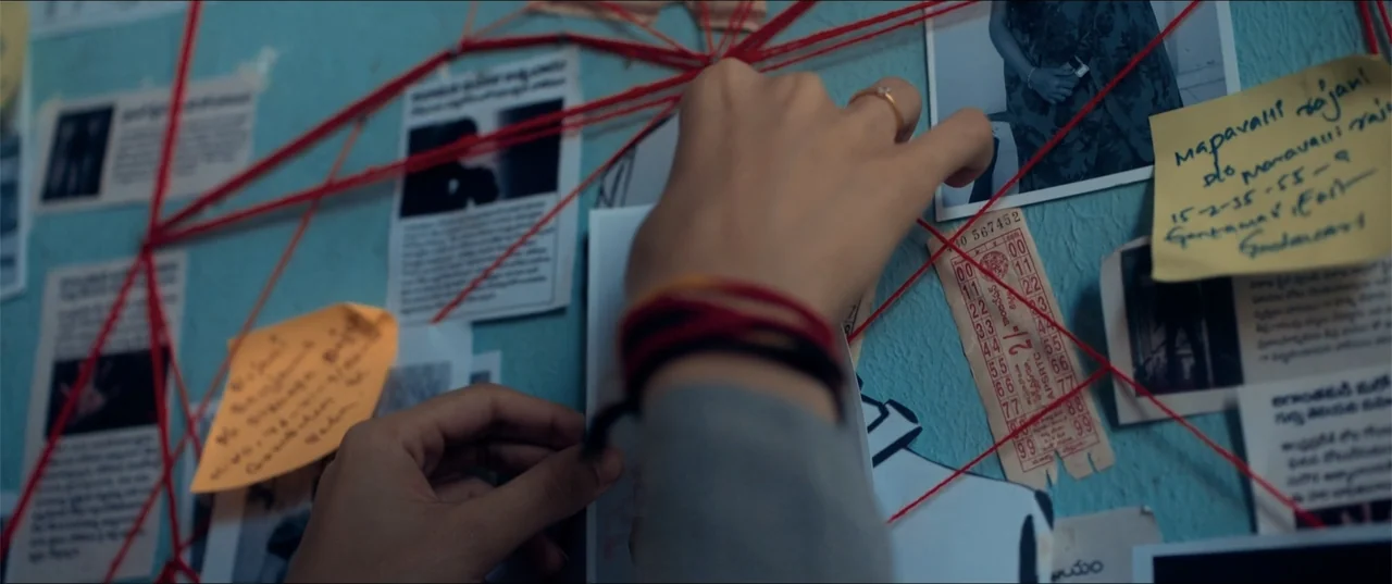 Cheekatilo (2026) movie still: closeup — A light blue wall is covered in evidence photos and yellow sticky notes. Red yarn connects the various…