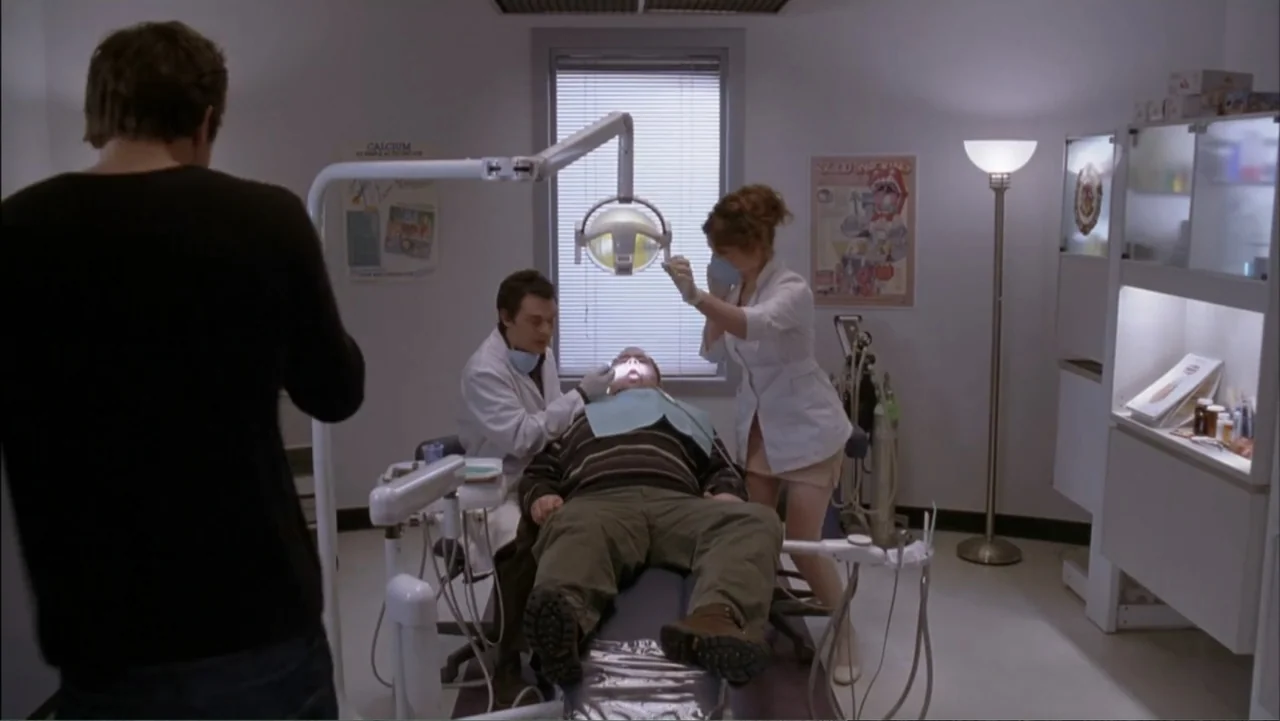 Just Friends (2005) movie still: medium — A sterile dental examination room with a white walls and tiled floor. A dentist and assistant perform a…