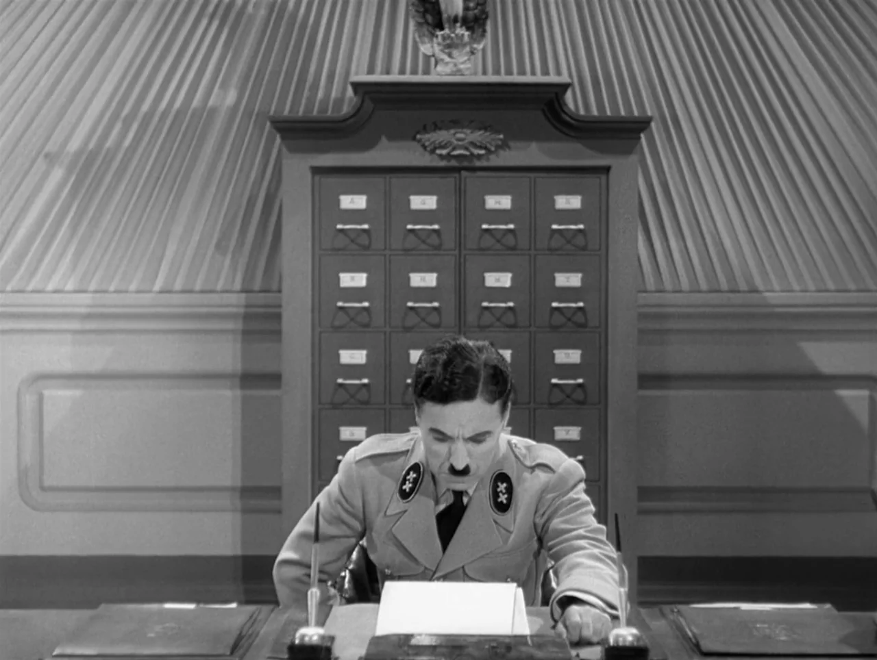 The Great Dictator (1940) movie still: medium — A government office with a large wooden card catalog cabinet behind a desk. A man in a military…