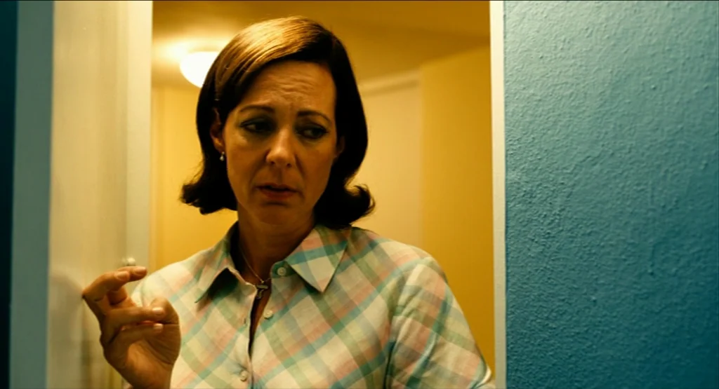 Life During Wartime (2009) movie still: medium — A woman stands within a doorway connecting a blue room to a yellow room. She holds her hand up…