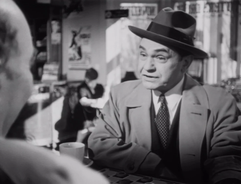The Stranger (1946) movie still: medium — A diner booth interior features a checkerboard laid out on the table surface. A man in a fedora sits…