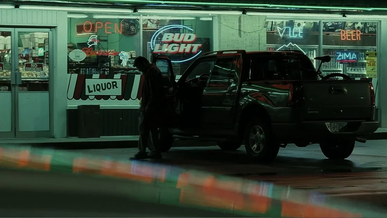 Mr. Brooks (2007) movie still: medium — A night exterior showing a dark pickup truck parked before a glowing storefront. A man wearing a dark jacket…