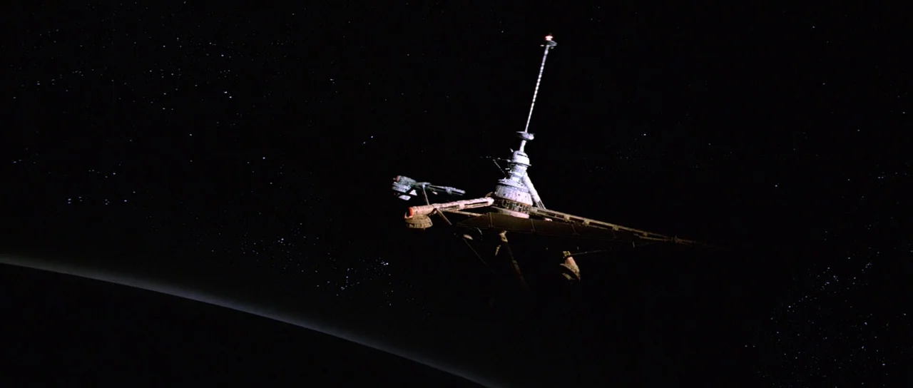 Moonraker (1979) movie still: establishing — A complex metallic space station floats in the darkness of deep outer space. A curved black planet…