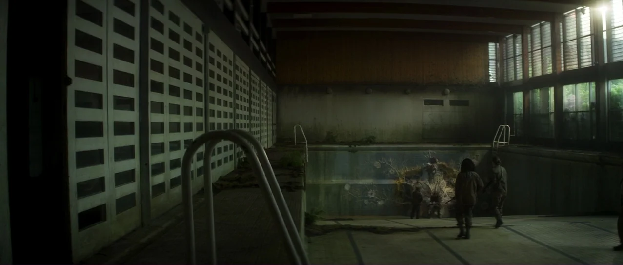 Annihilation (2018) movie still: wide — An abandoned indoor pool features tiled floors, rows of white slatted windows, and mossy buildup. Two…