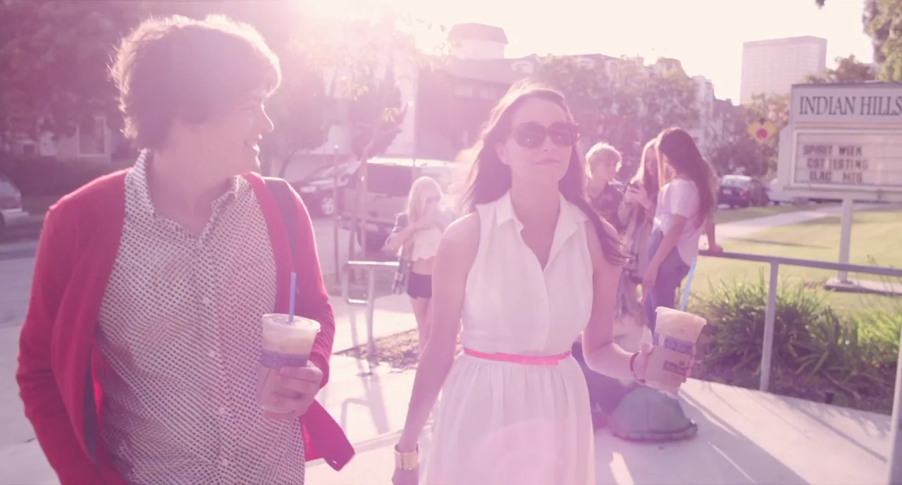 The Bling Ring (2013) movie still: medium — A bright outdoor campus area features a marquee sign and suburban buildings. A young couple walks…