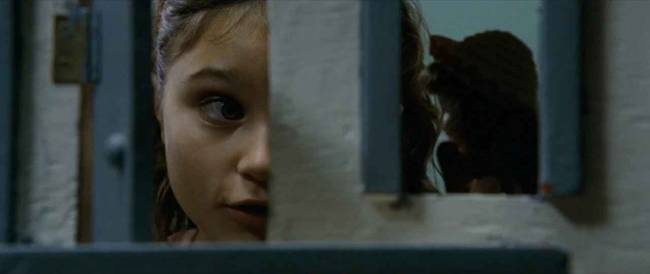 The Haunting in Connecticut (2009) movie still: closeup — A dimly lit indoor space features a wall partition next to a reflective mirror. A young…
