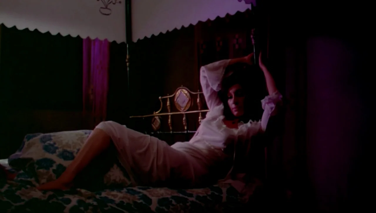 The Return of the Prodigal Son (1978) movie still: medium — A dark, dimly lit room contains a four-poster bed with ornate metal details. A woman in…