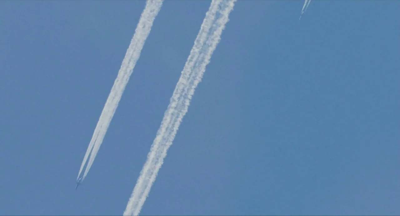 Snowpiercer (2013) movie still: establishing — A clear blue sky serves as the backdrop for three distinct white vapor trails. Three distant…