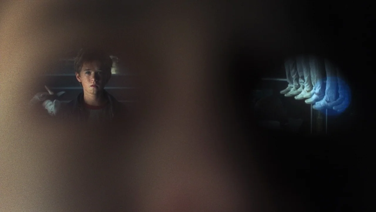 A.I. Artificial Intelligence (2001) movie still: medium — A dark bedroom interior viewed through circular binocular lenses. A young boy stands on…