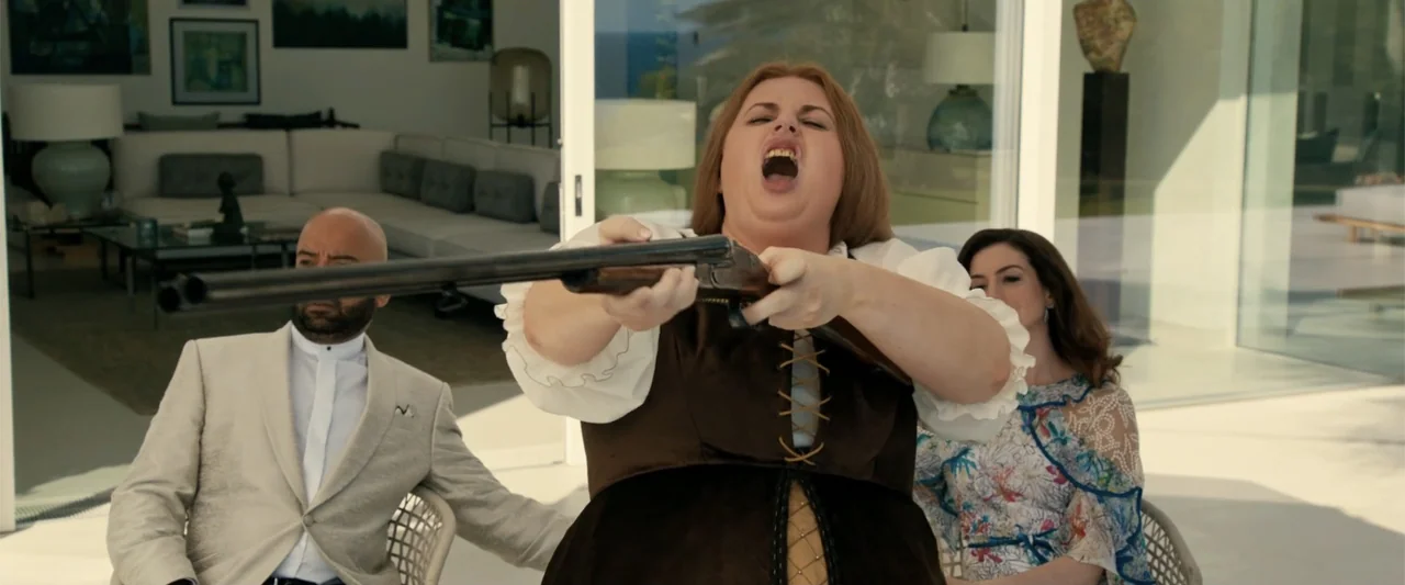 The Hustle (2019) movie still: medium — A modern, bright luxury villa patio features glass sliding doors and white furniture. A woman in…