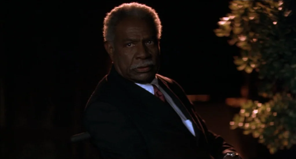 Bubba Ho-Tep (2002) movie still: closeup — An elderly man in a dark suit sits outdoors in the deep night darkness. He turns his head to face the…
