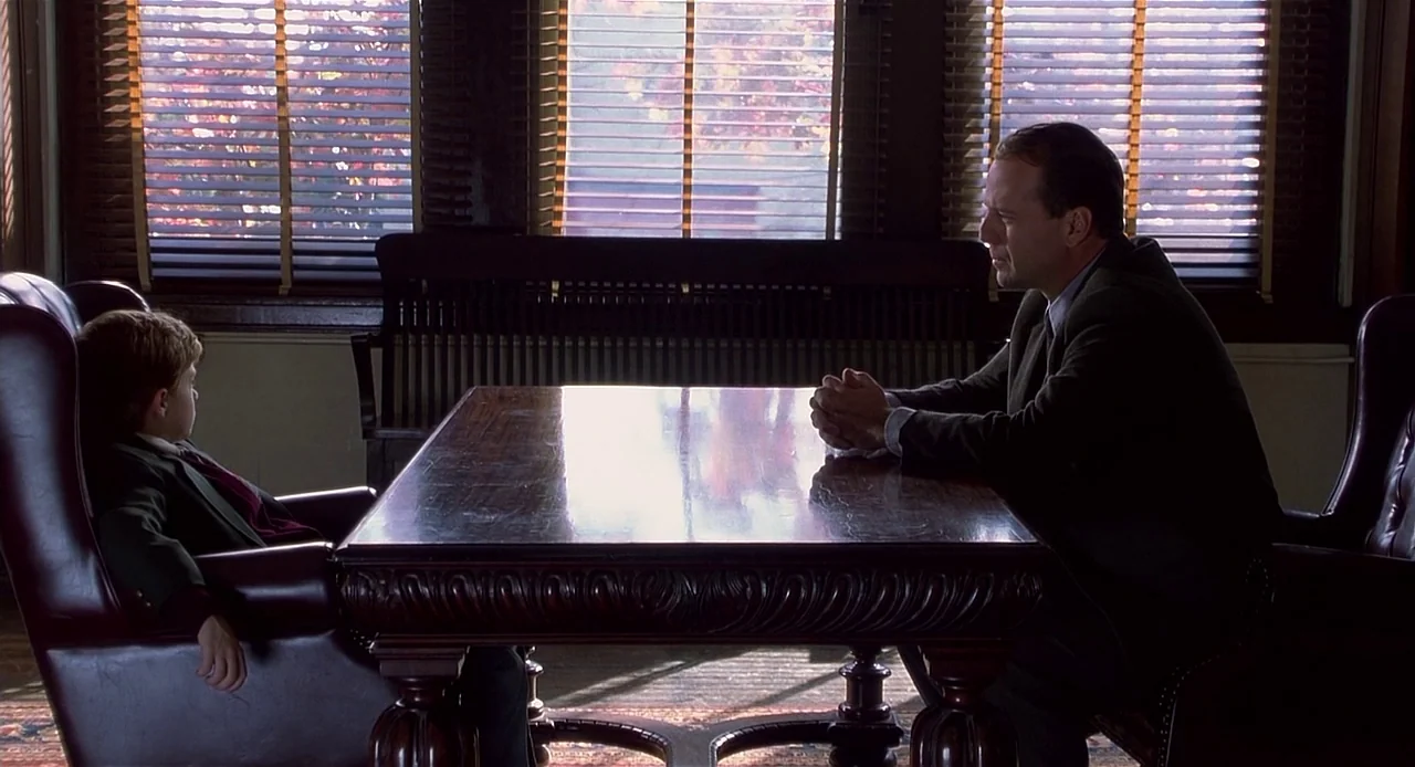 The Sixth Sense (1999) movie still: wide — A formal office space features a heavy wooden table and leather armchairs in front of windows with closed…