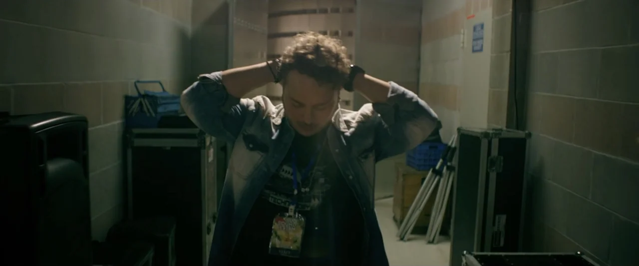 Taranta On the Road (2017) movie still: medium — A cramped storage room features grey tiled walls and stacked black production equipment cases. A…