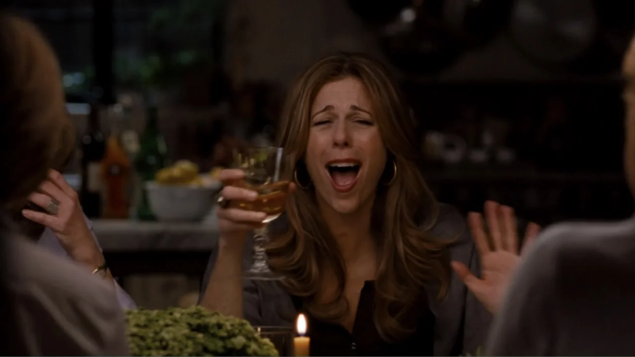 It's Complicated (2009) movie still: medium — A dimly lit dining room features a table set with wine and candles. A woman sits in the center of the…