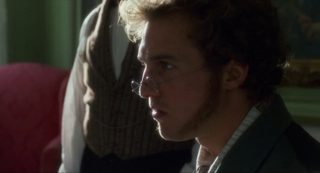 Amistad (1997) movie still: closeup — A 19th-century room with dark furniture and upholstered chairs. A man in period clothing sits while another…