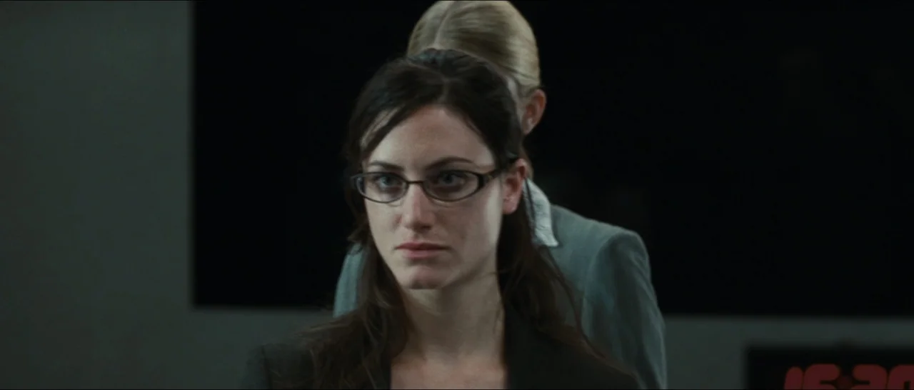 Slackers (2002) movie still: closeup — An office interior features two women standing in a well-lit space. The primary subject in the foreground…
