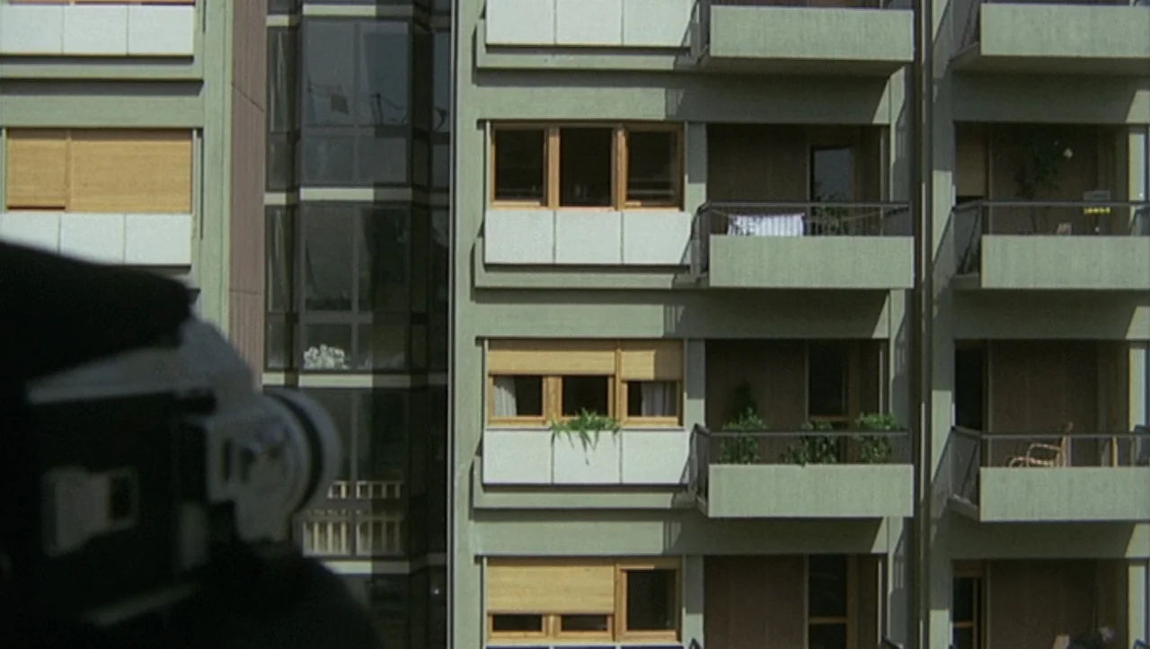 The Black Belly of the Tarantula (1971) movie still: medium — A green multi-story residential building facade with multiple balconies and wooden…