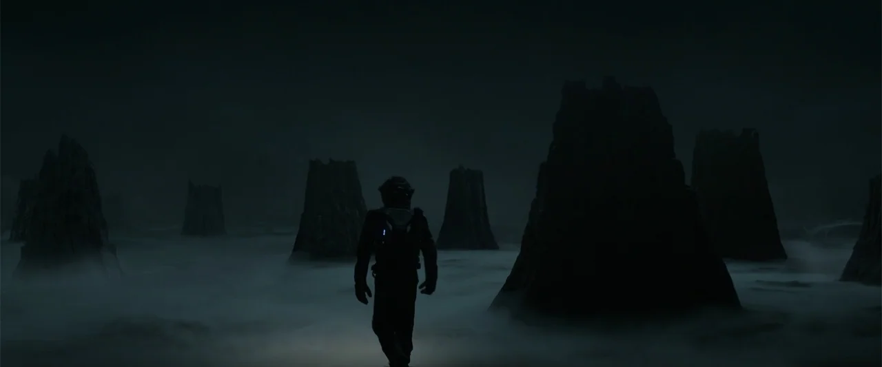 DISTANT (2026) movie still: fullbody — A dark alien landscape features jagged rock pillars emerging from a low-lying dense fog. A solitary figure in…