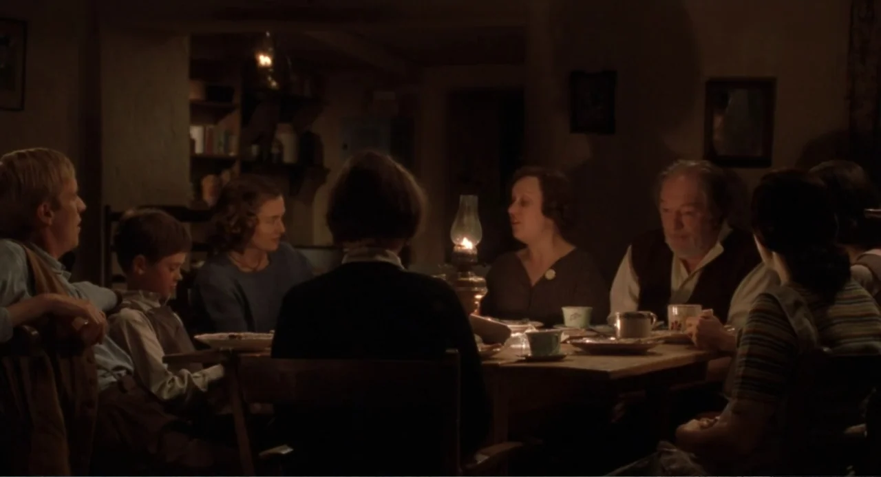 Dancing at Lughnasa (1998) movie still: medium — A rustic dining room features wooden furniture and dim, warm lighting from an oil lamp. A family is…