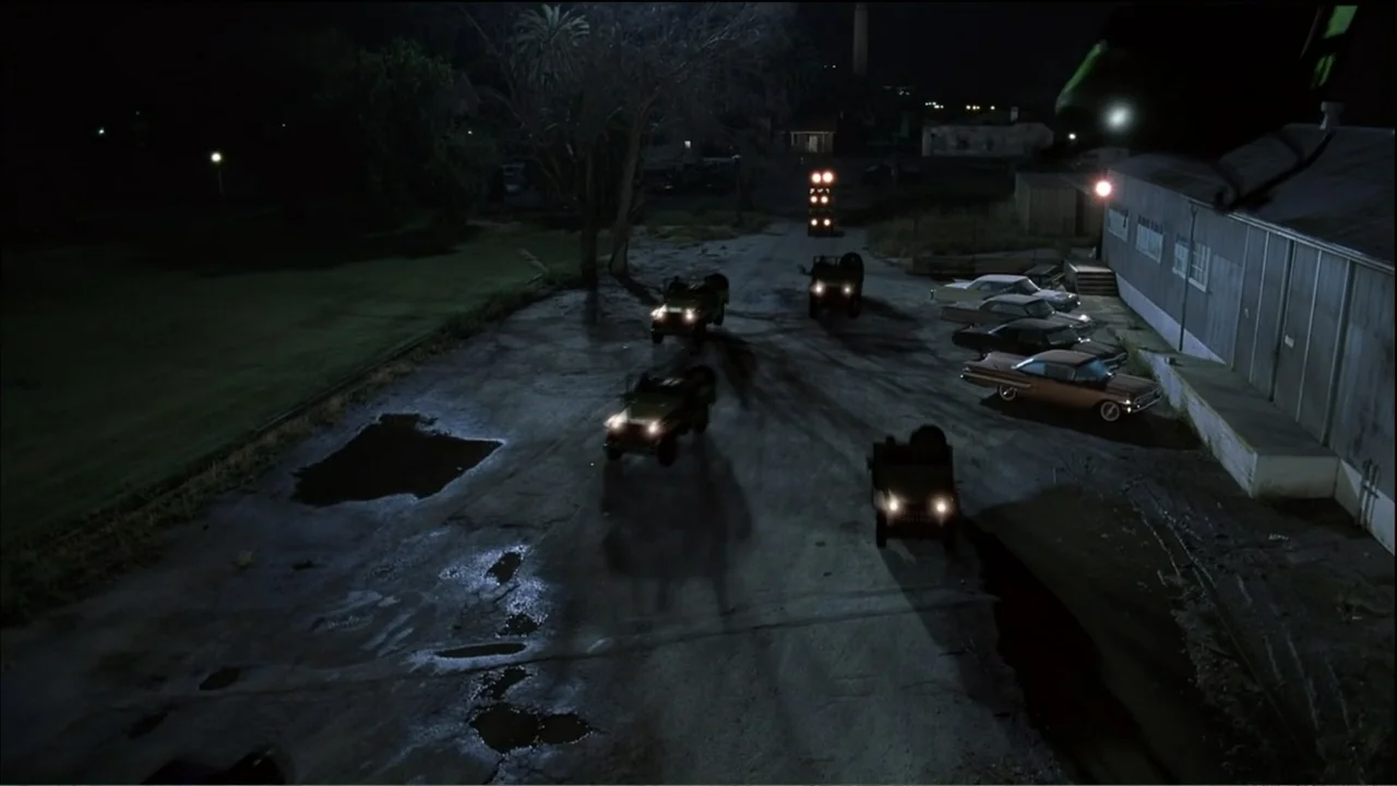 Day of the Dead 2: Contagium (2005) movie still: wide — An industrial concrete lot at night features several vintage vehicles and parked classic…