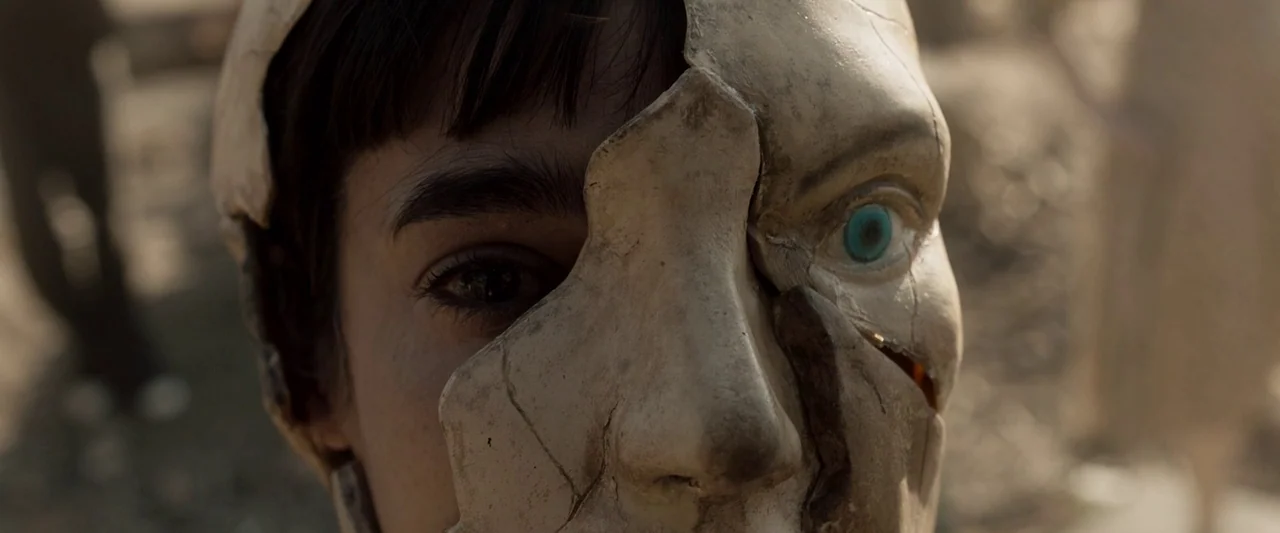 Prisoners of the Ghostland (2021) movie still: closeup — An outdoor area with a textured, dusty ground surface visible in the blurred background. A…