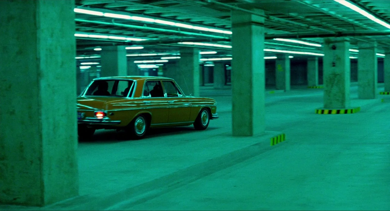 The Driver (1978) movie still: wide — A vast underground concrete parking facility features rows of massive square support columns. A vintage yellow…