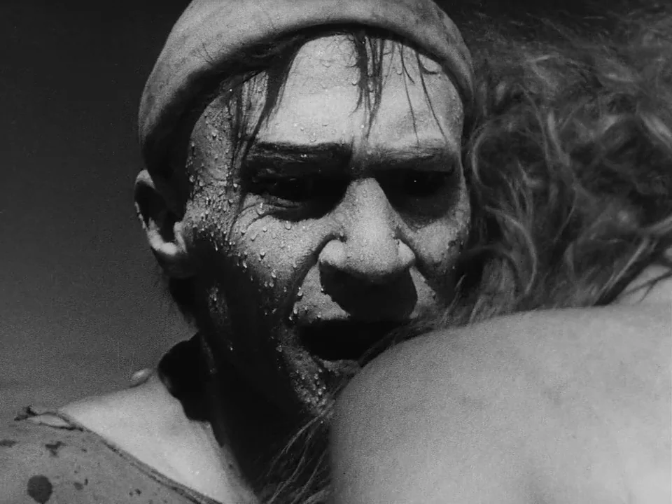 Sawdust and Tinsel (1953) movie still: closeup — An undifferentiated dark space focuses closely on two individuals in an embrace. A wet, disheveled…