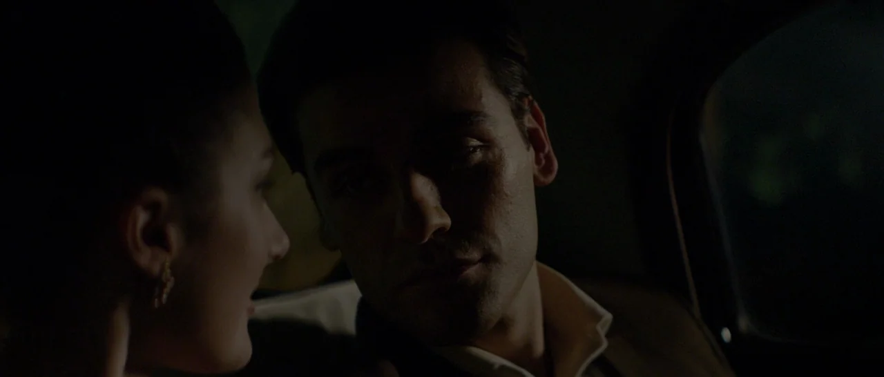 The Two Faces of January (2014) movie still: closeup — A dark car interior at night with faint light entering through the window. A man and a woman…