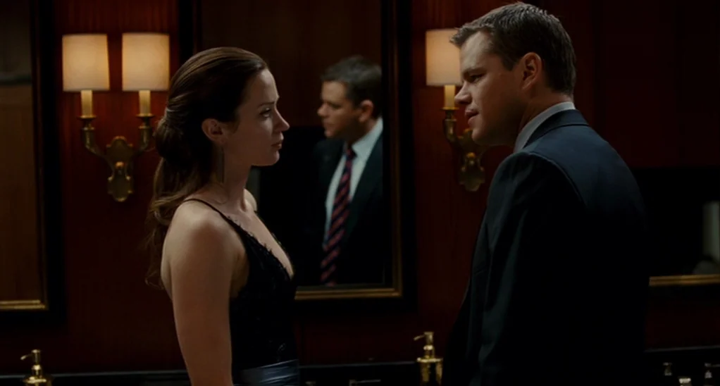 The Adjustment Bureau (2013) movie still: medium — A dimly lit restroom with dark wood paneling and ornate wall sconces. A man and a woman stand…