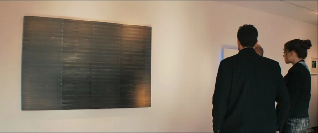 The Girlfriend Experience (2009) movie still: medium — A minimalist gallery space features white walls and a large, dark rectangular abstract…