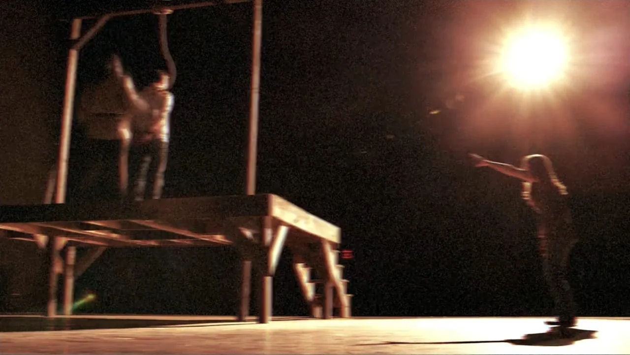 The Gallows (2015) movie still: wide — A wooden gallows platform stands in a dark outdoor setting at night. A woman stands in the foreground with…