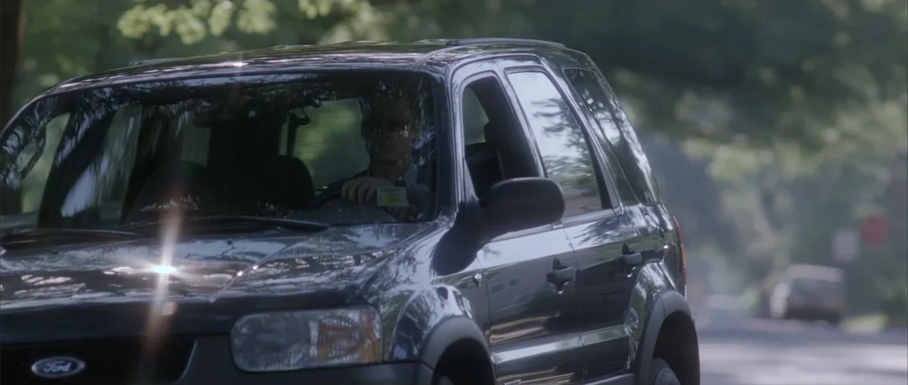 A Walk to Remember (2002) movie still: medium — A dark SUV travels along a road framed by out-of-focus green trees. A man with sunglasses sits in…